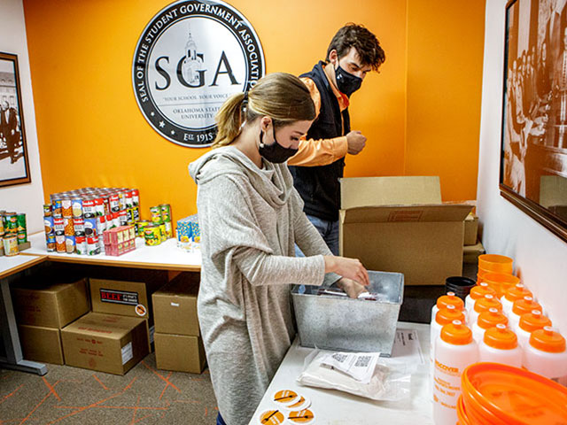 Two masked students prepare food donation boxes in OSU's Student Government Association office.