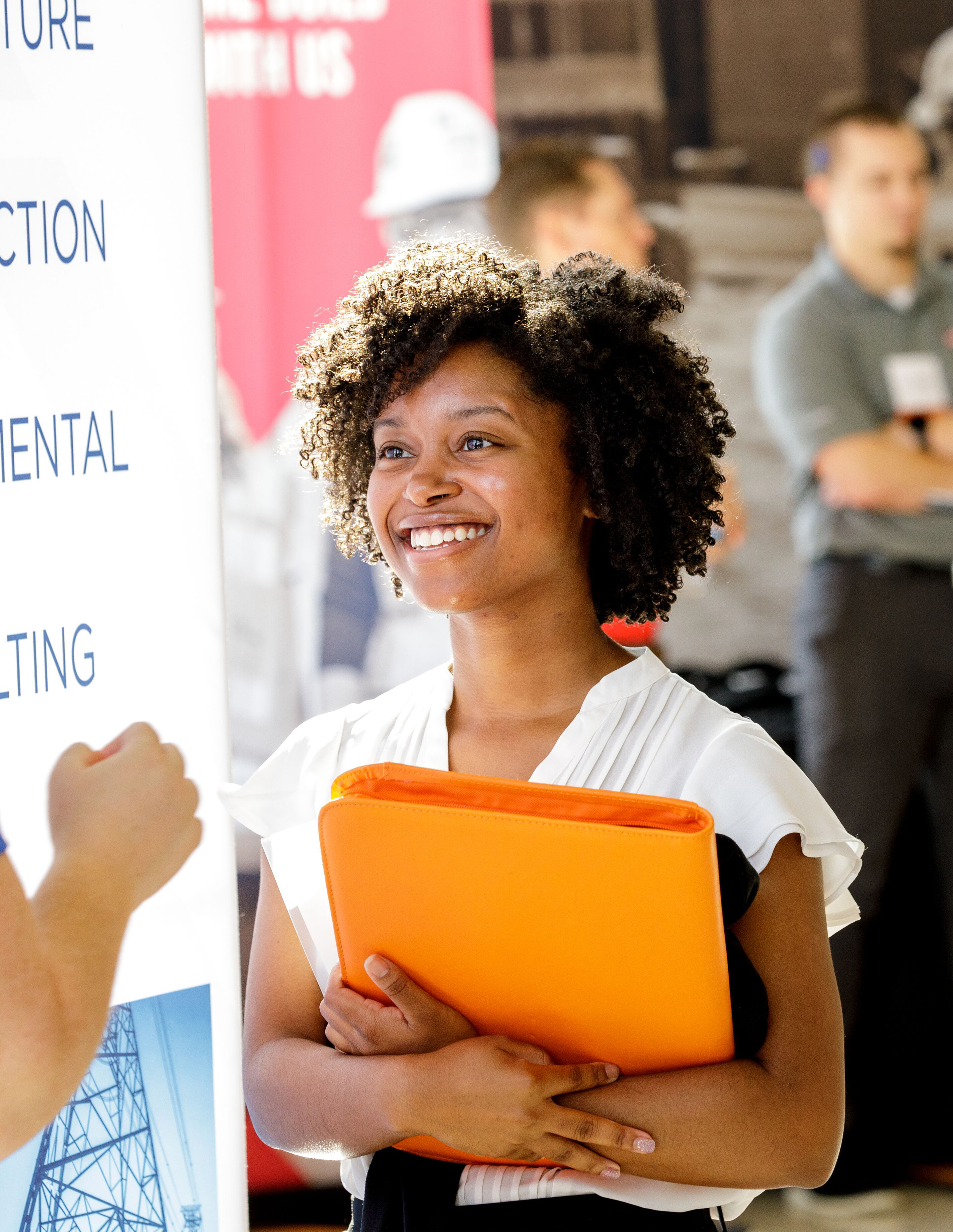An image of a woman smiling with an orange briefcase. 
