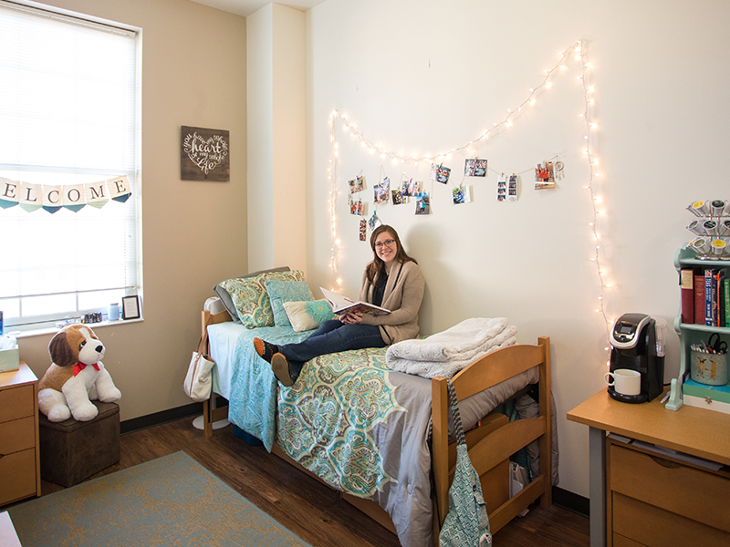 Student sitting on bed in the Commons