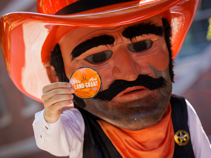 Photo of Pistol Pete holding up a sticker that says Photo of Pistol Pete holding up a sticker that says